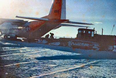 D8 tractor with sled backed up to a C-130 off-loading supplies